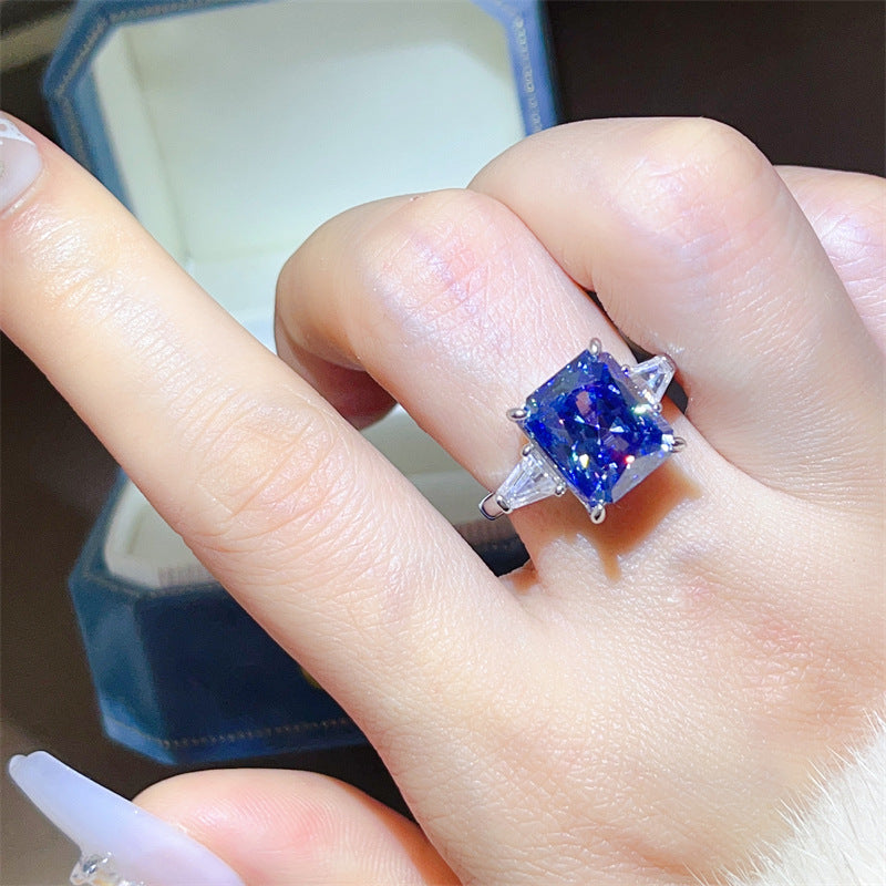 Blue gemstone ring on a finger with a blurred background