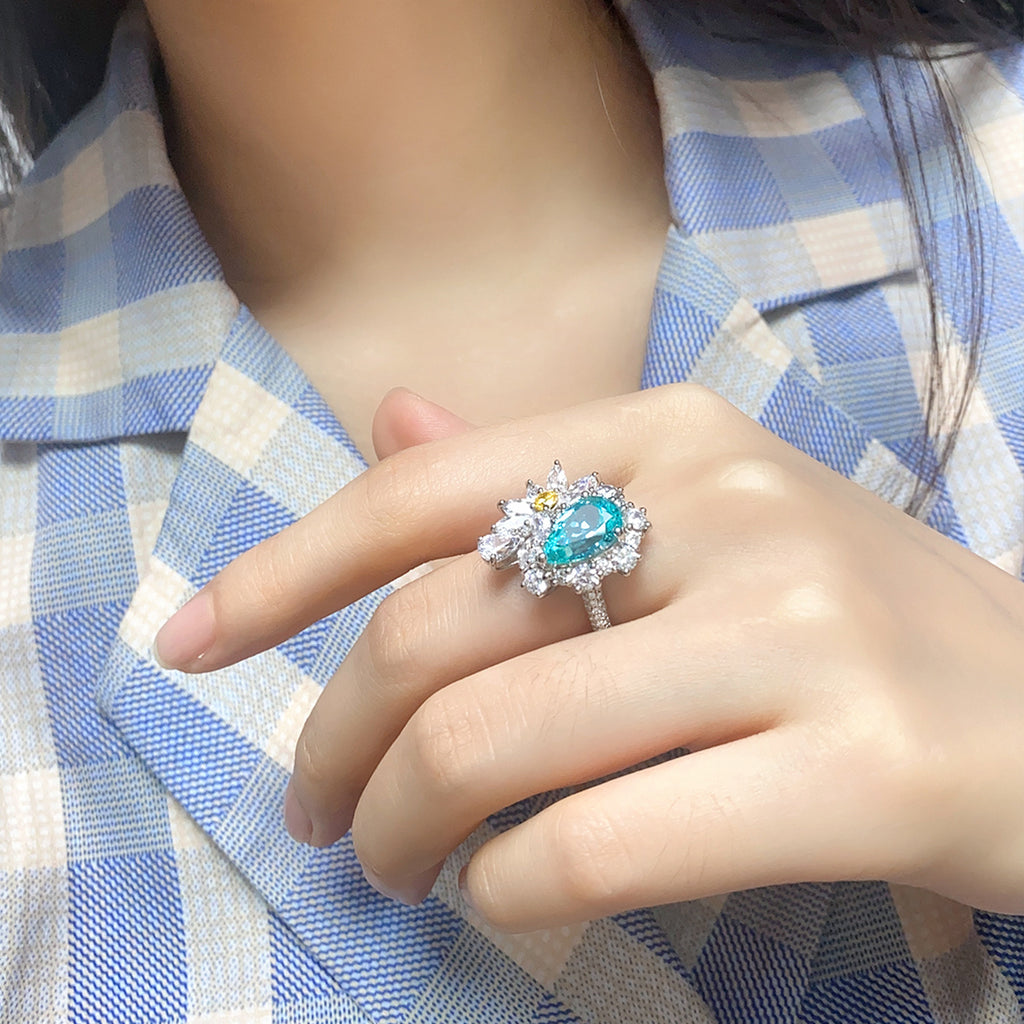 Close-up of a hand wearing a ring with a blue gemstone on a checkered fabric background