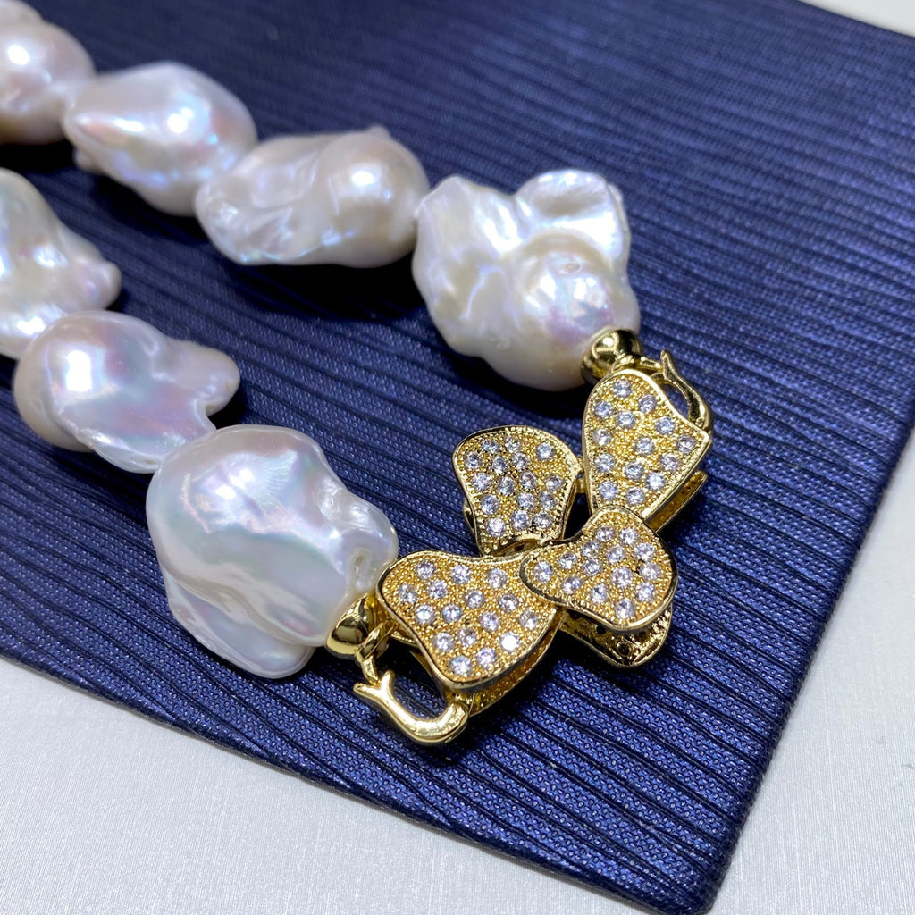 Pearl necklace with a gold butterfly pendant on a blue fabric background