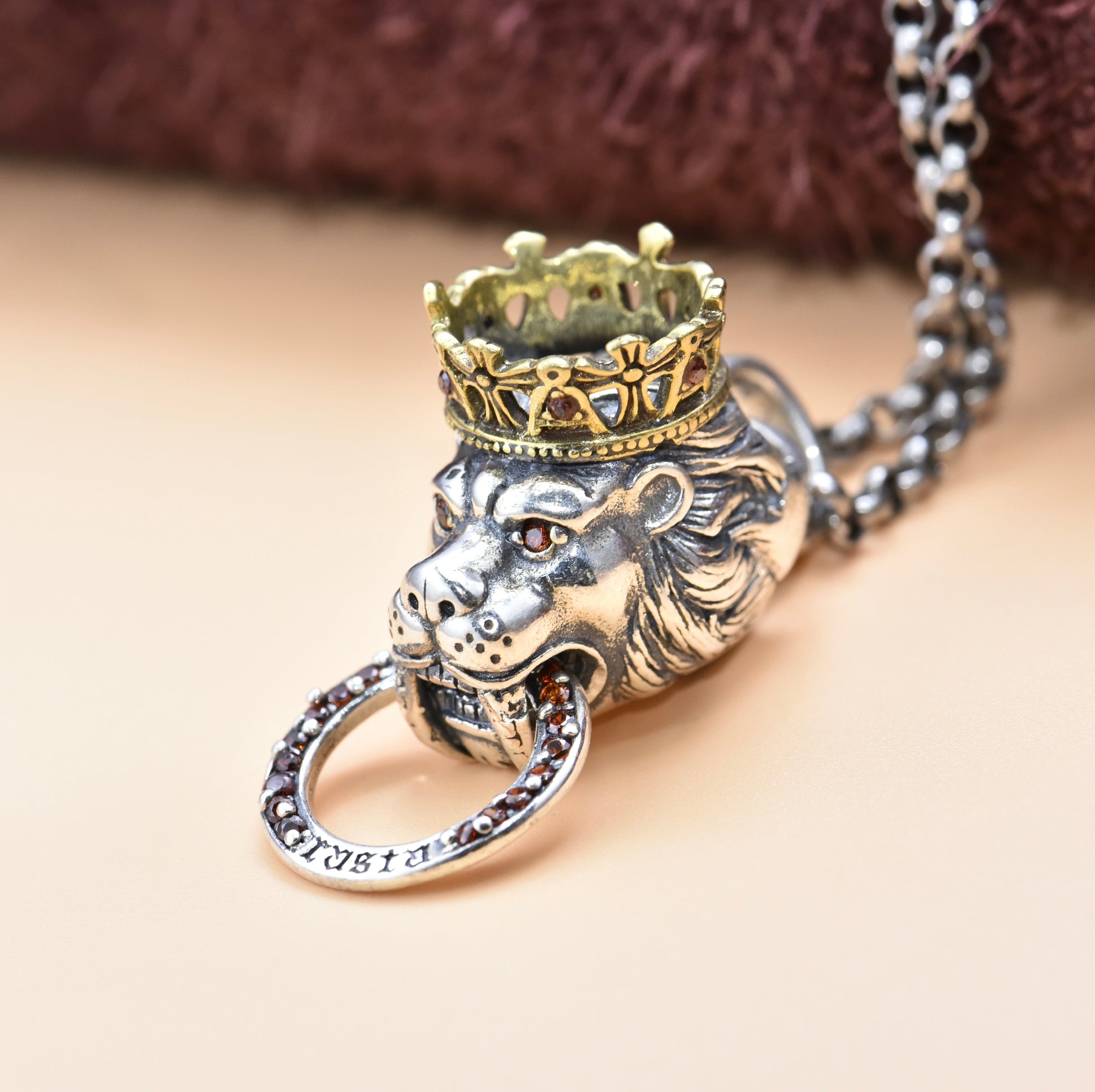 Lion head pendant with crown and chain on a beige background