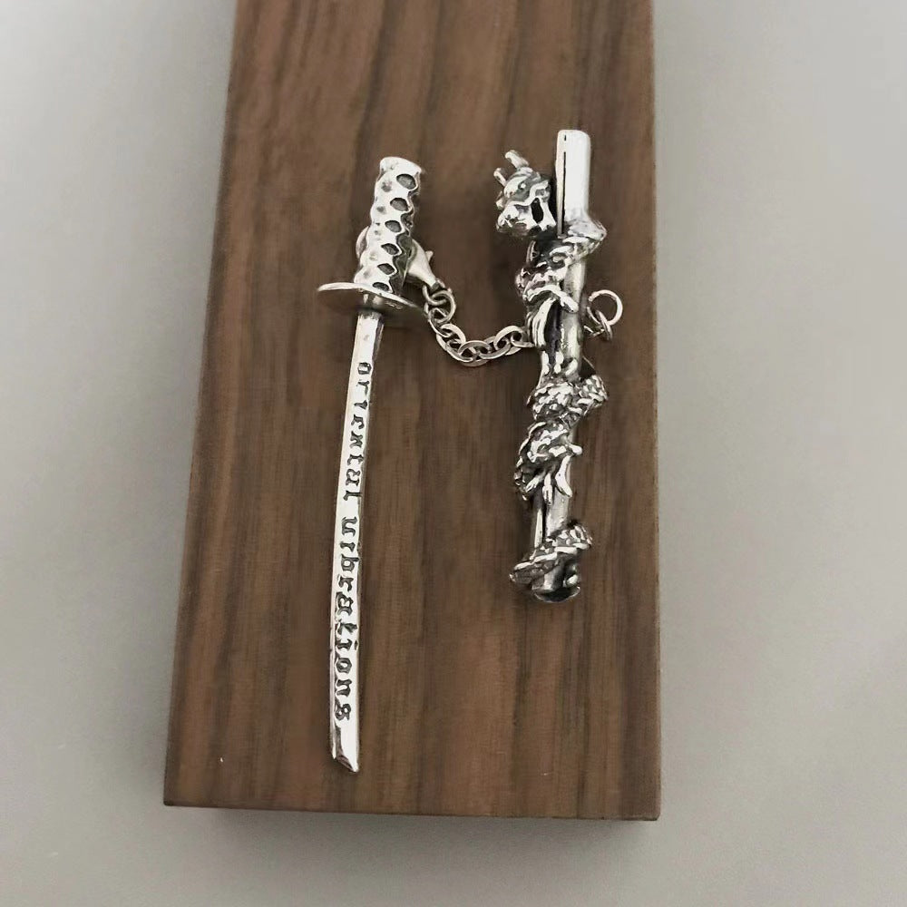 Silver sword and sheath keychain on a wooden block