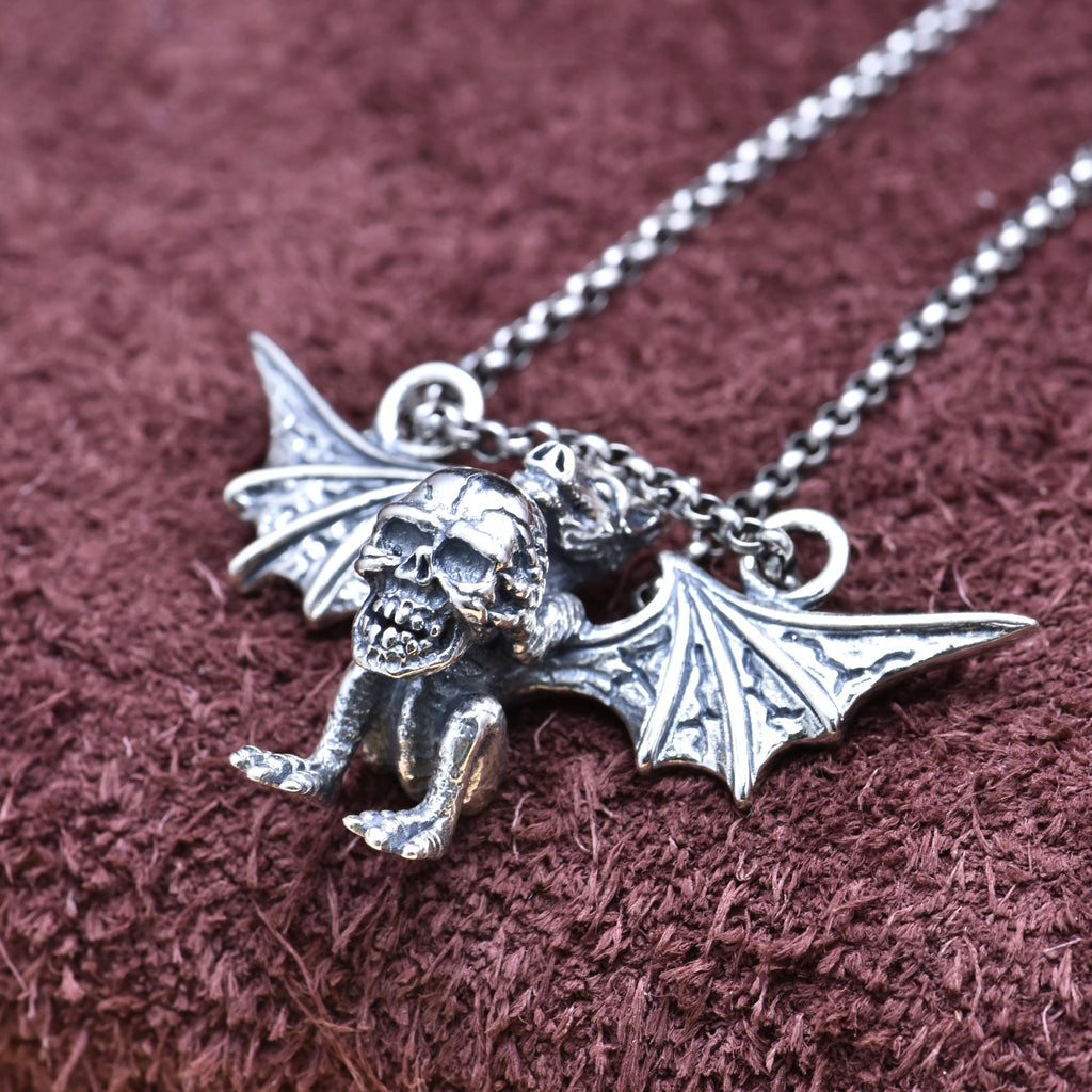 Silver gargoyle pendant necklace on a textured brown background