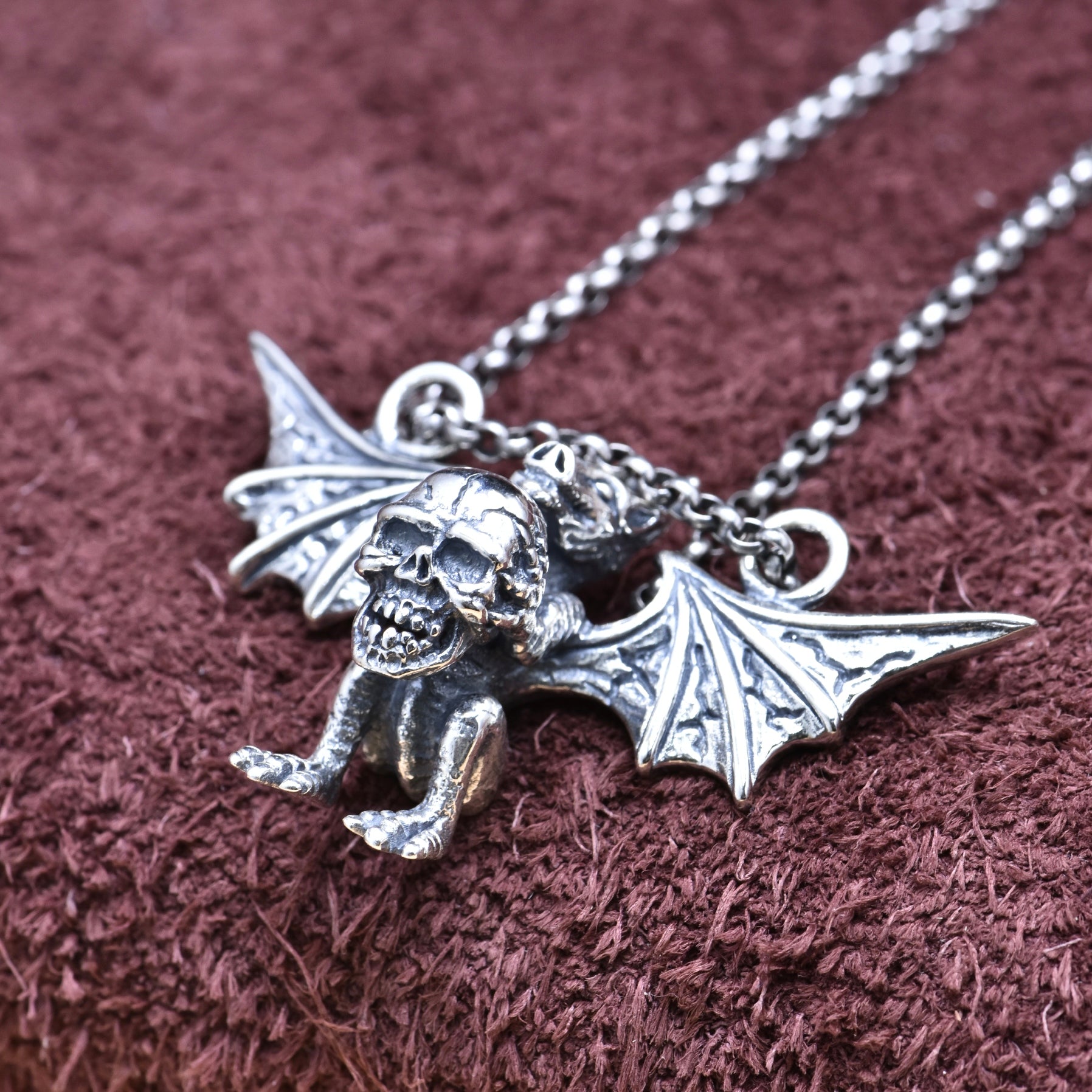 Silver gargoyle pendant necklace on a textured brown background