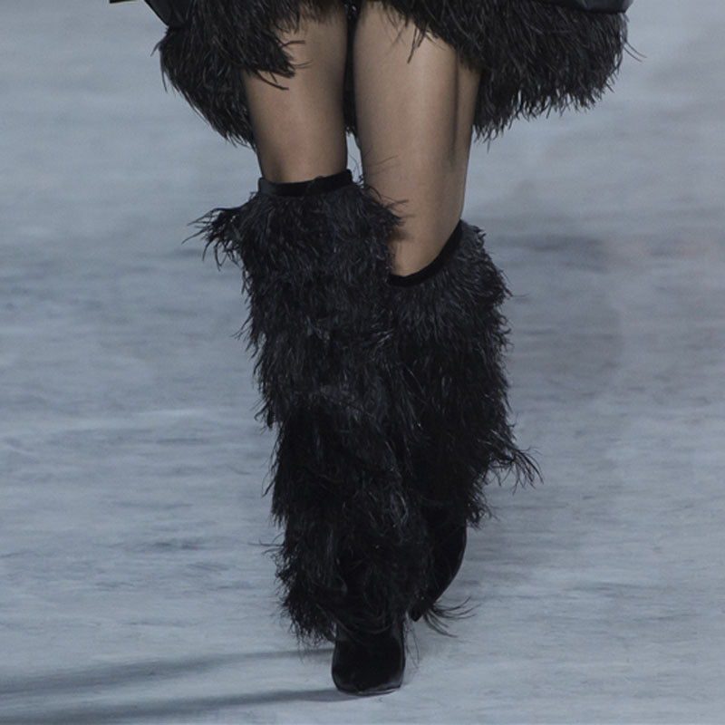 Black feathered boots worn on a blurred background