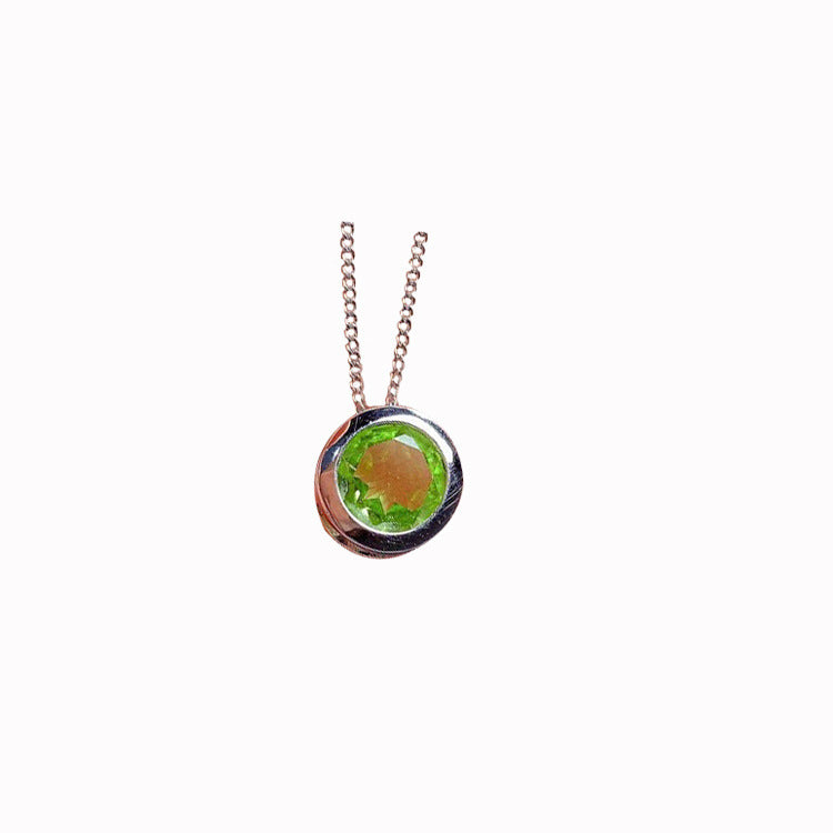 Small round pendant with a green gemstone on a thin chain against a white background