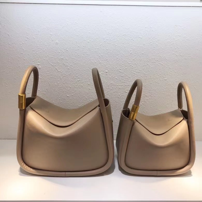 Two beige handbags with gold accents on a light gray background