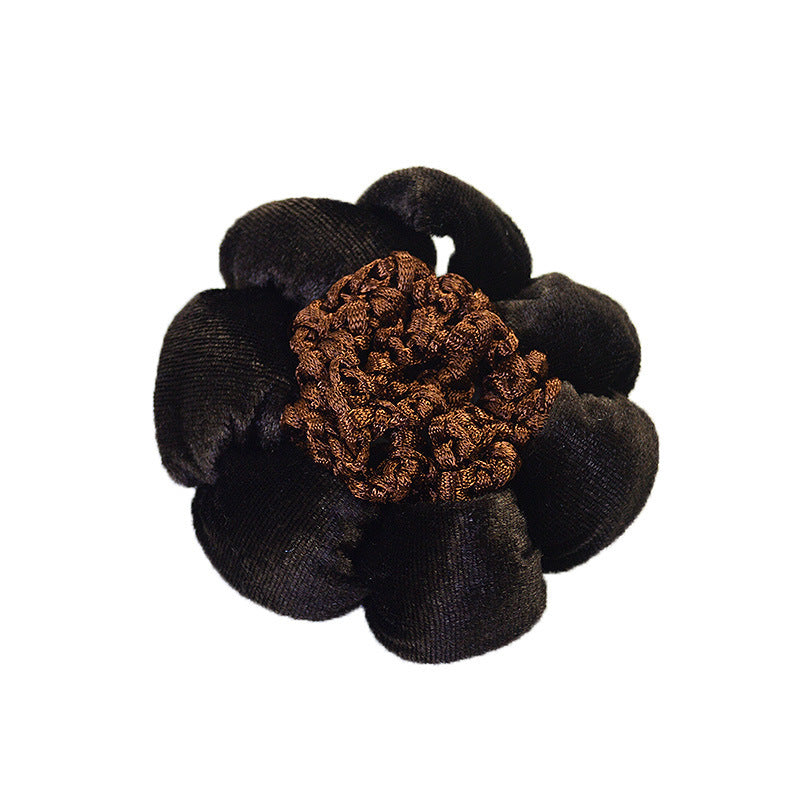 Black flower-shaped hair scrunchie with a brown center on a white background
