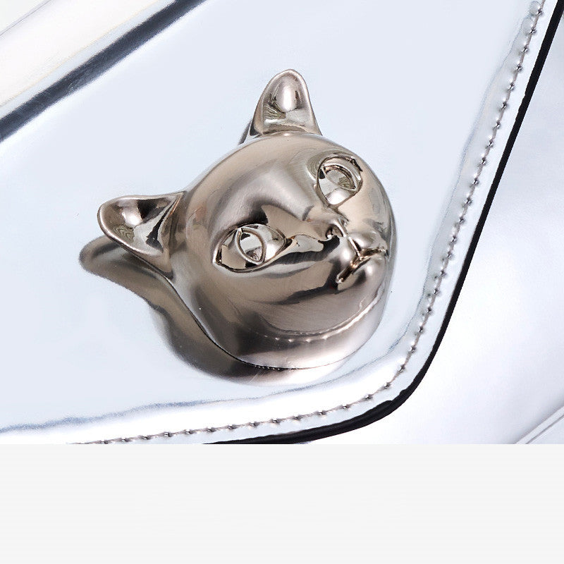 Metallic cat-shaped object on a white surface