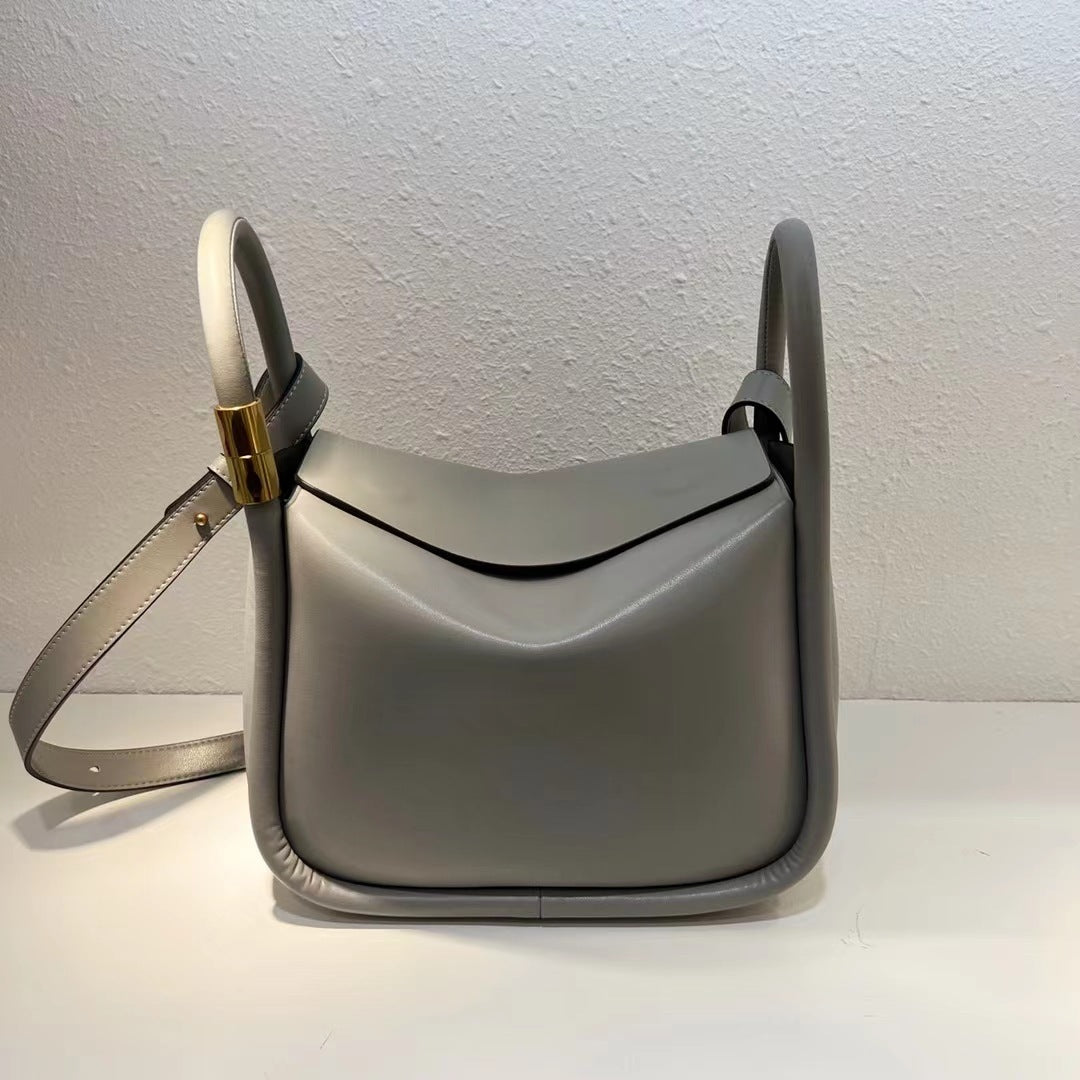Gray handbag with a strap on a white surface and light gray background