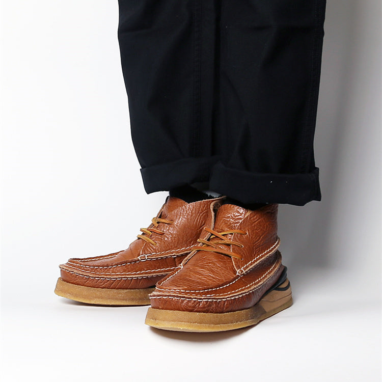 Brown leather shoes worn with black pants on a white background