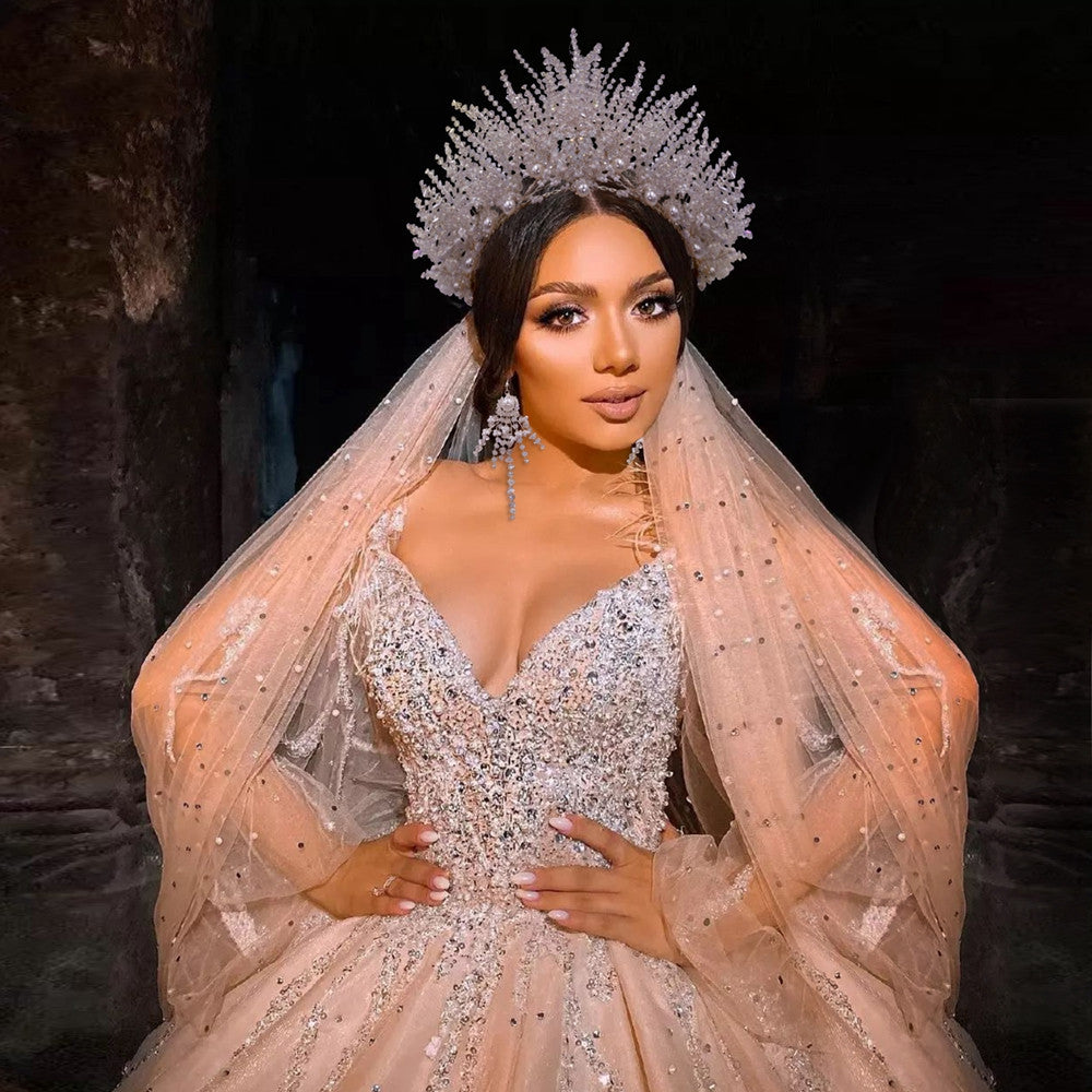 Woman in a sparkling gown with a large headpiece against a dark background