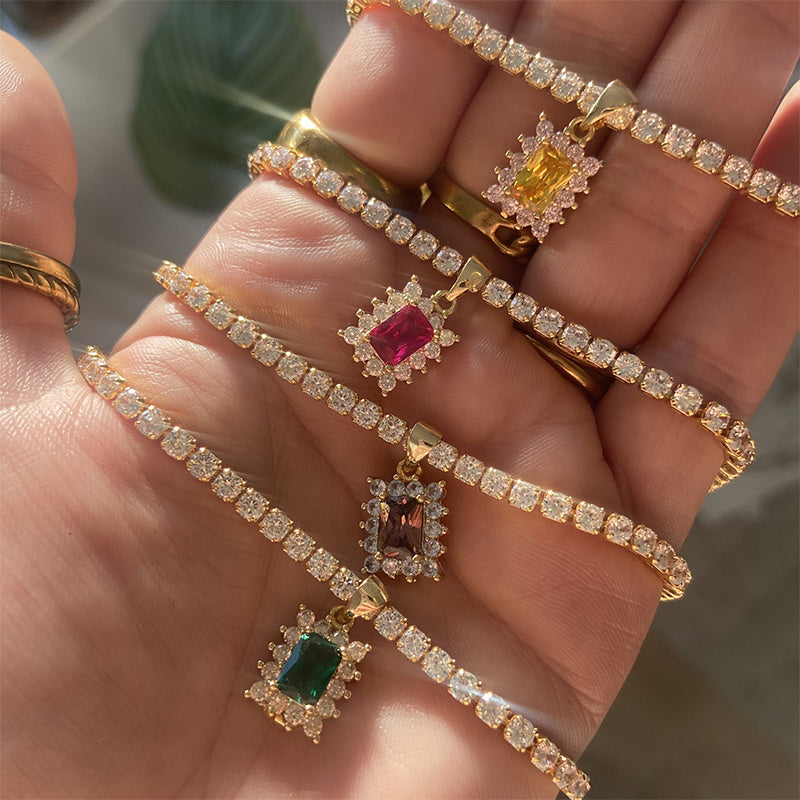 Gold jewelry with gemstone pendants on a hand