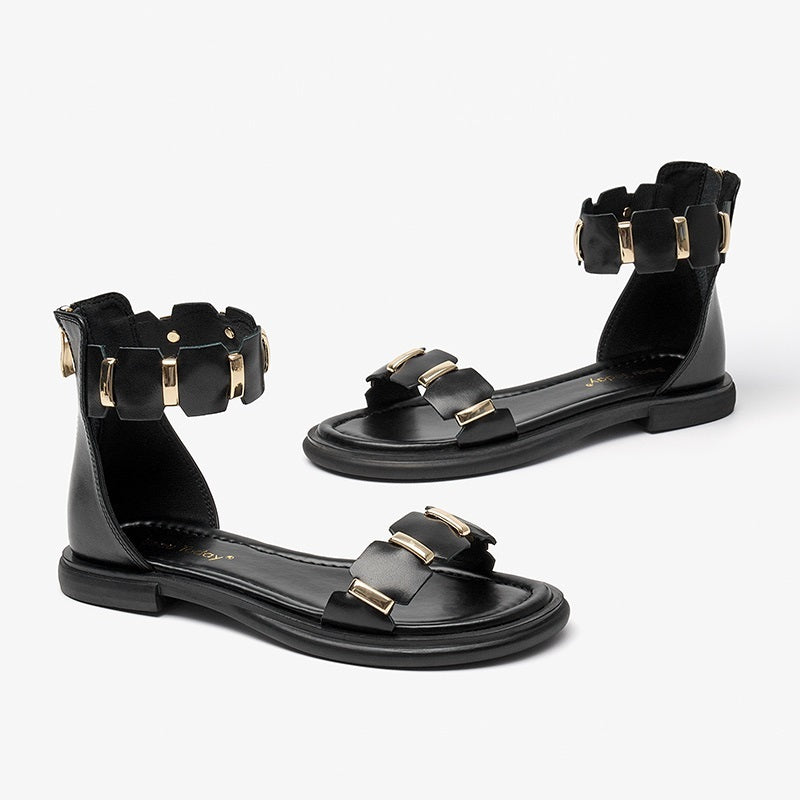 Black sandals with gold accents on a white background