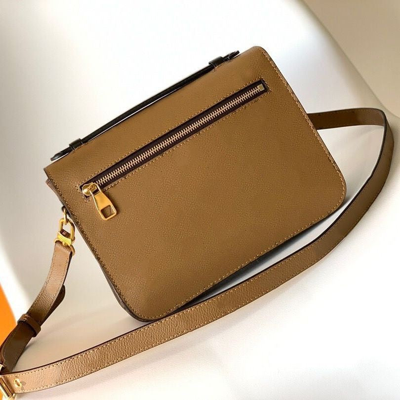 Brown leather handbag with a gold zipper on a light background