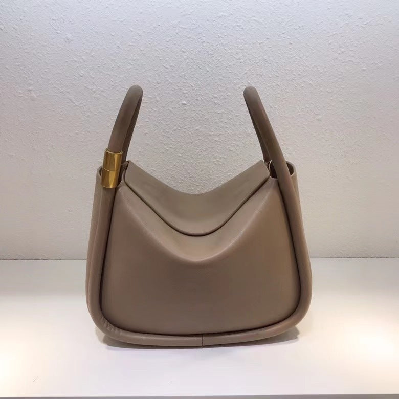 Beige handbag with gold clasp on a white background