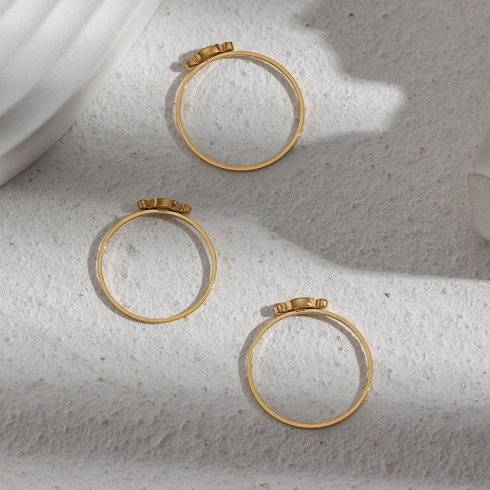 Three gold hoop earrings on a textured white surface