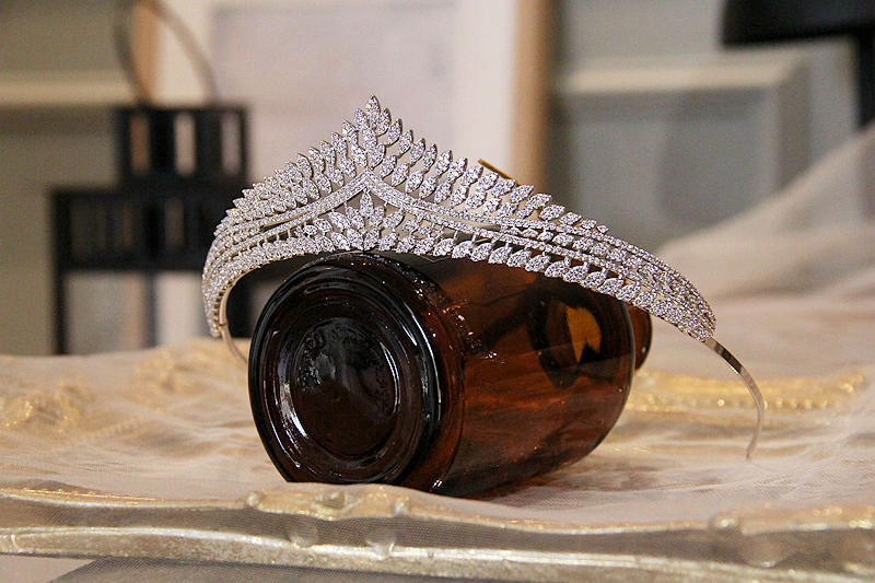 Camera with a decorative silver headband on top, placed on a reflective surface.