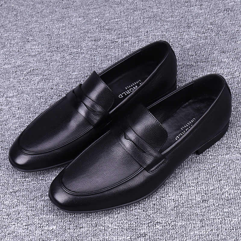 Pair of black leather loafers on a textured gray surface