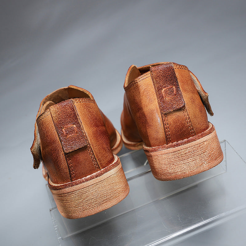 Pair of brown leather shoes on a clear stand against a gray background