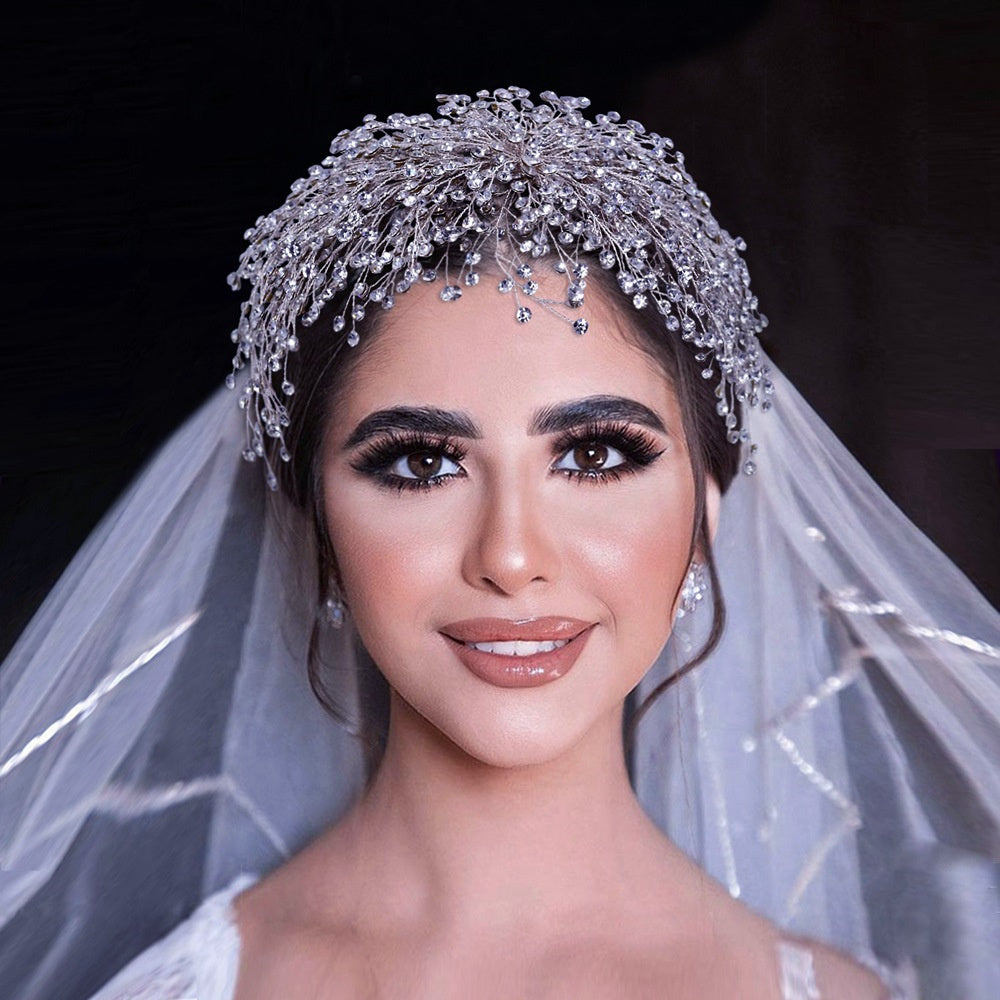 Bride wearing a sparkling headpiece and veil against a dark background