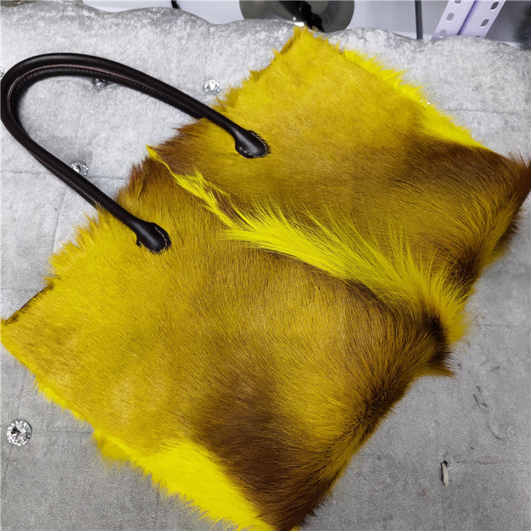 Yellow and brown fur fabric with a black handle on a gray surface