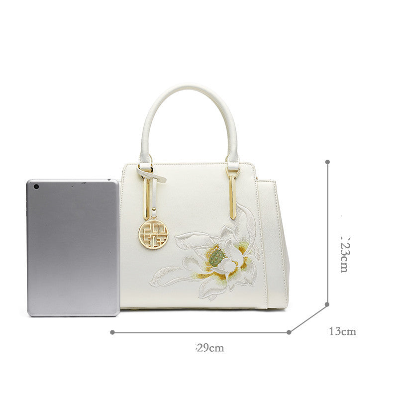 White handbag with floral design and measurements on a white background