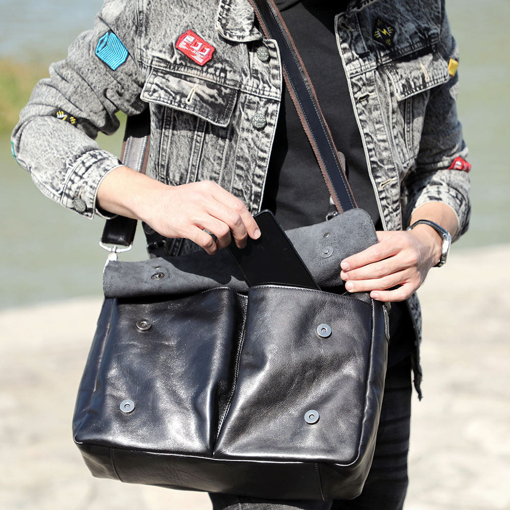 Person holding a black leather bag with a blurred background