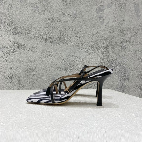 Black and white striped sandal on a textured surface with a gray background