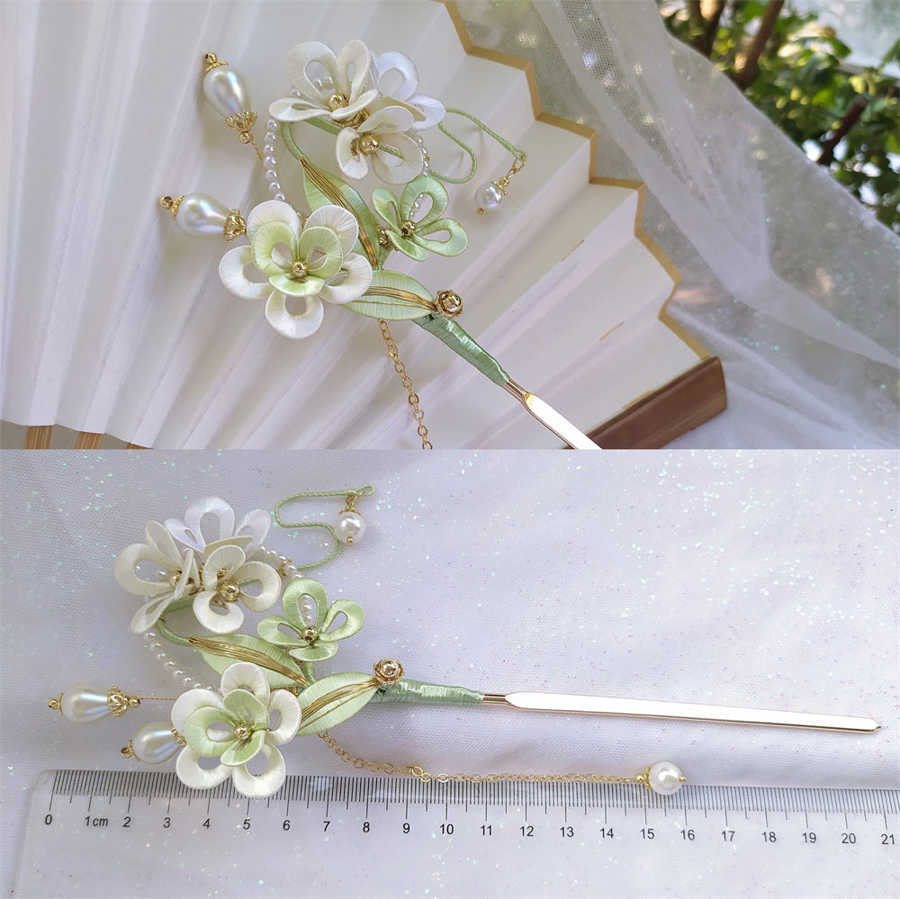 Decorative hairpin with floral design and pearls on a white surface with a ruler for scale.