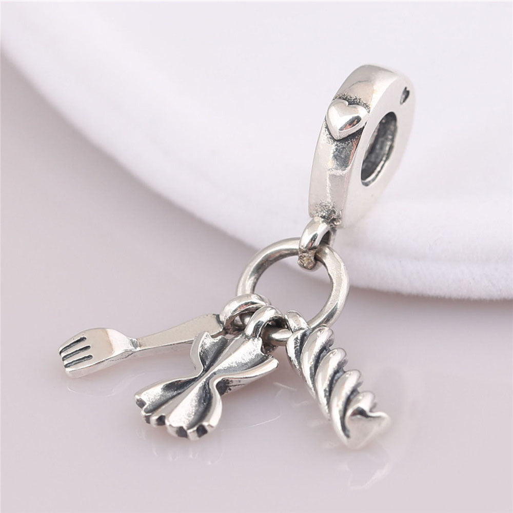 Silver charm with a fork and pasta shape on a light background
