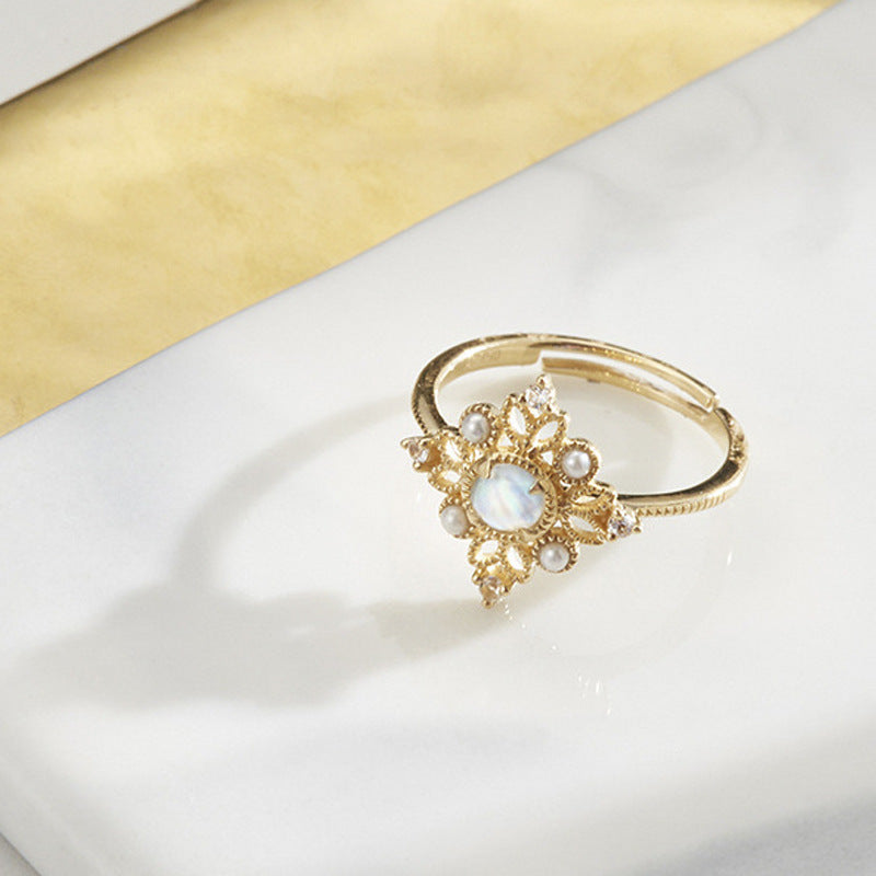 Gold ring with pearl-like stones on a white and gold background