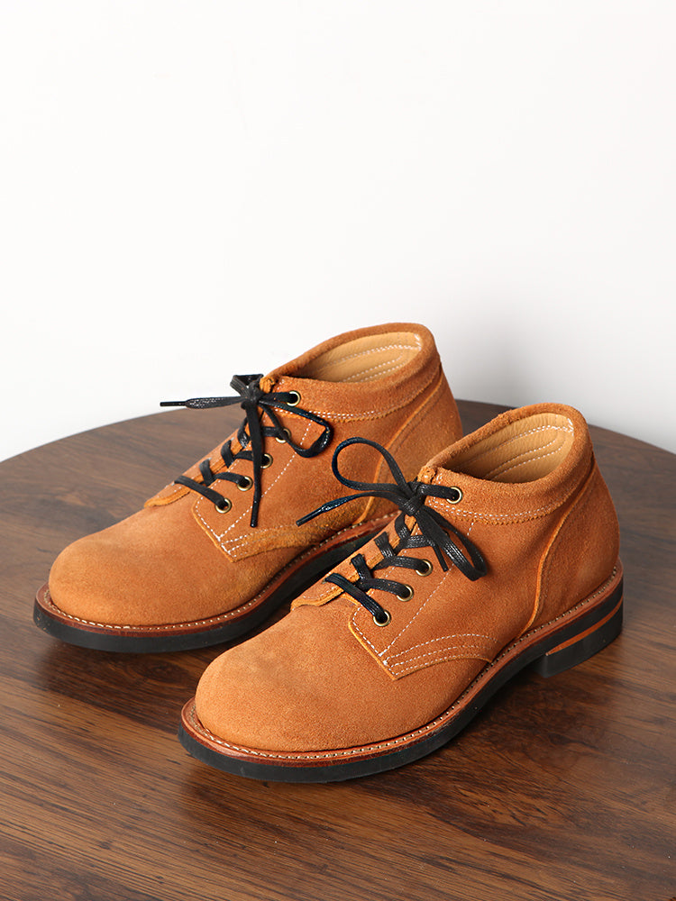 Pair of brown leather shoes with black laces on a wooden surface.