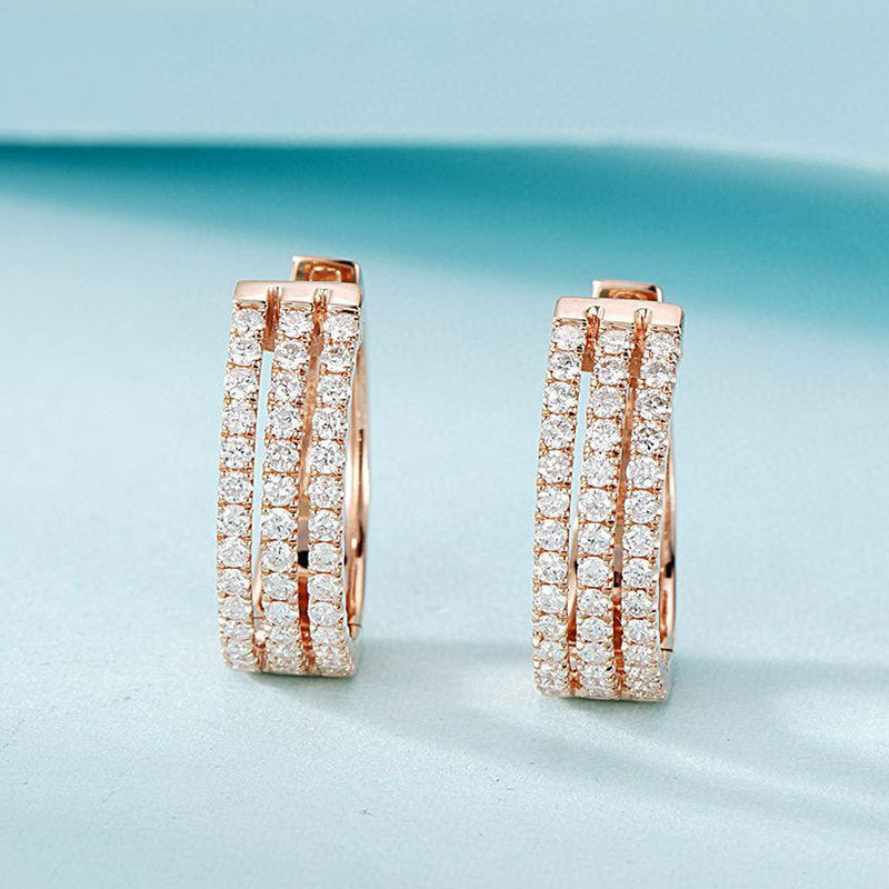 Rose gold hoop earrings with diamond accents on a light blue background