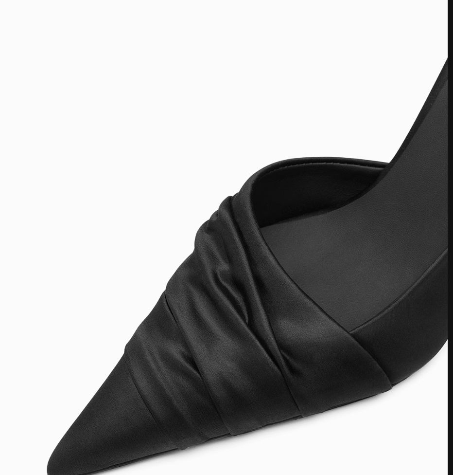 Black pointed-toe shoe with a knot detail on a white background