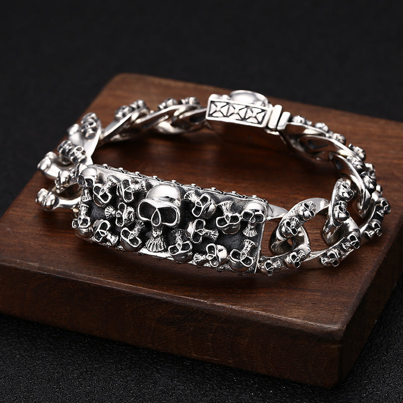 Silver skull-themed bracelet on a wooden stand with a dark background