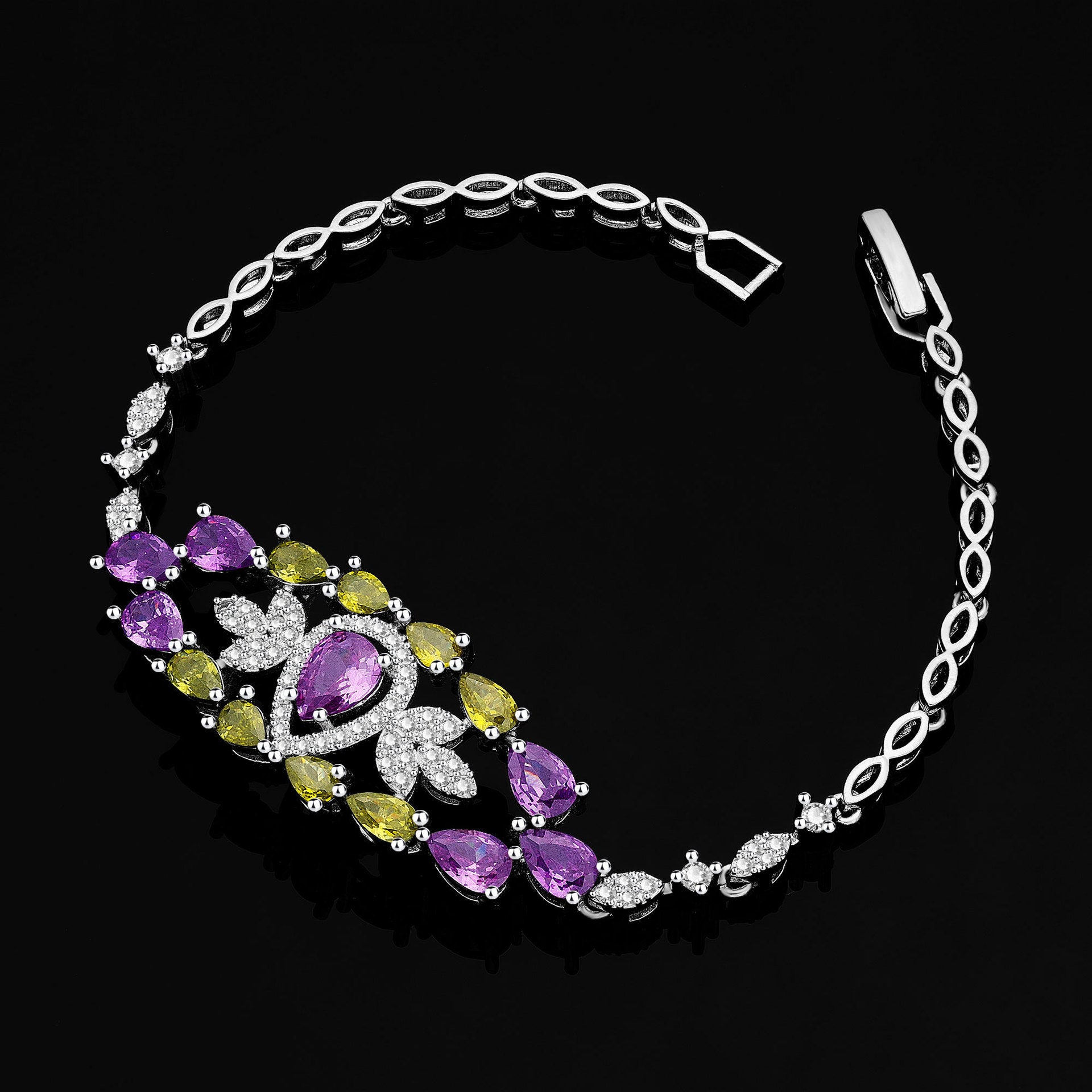 Silver bracelet with purple and green gemstones on a black background