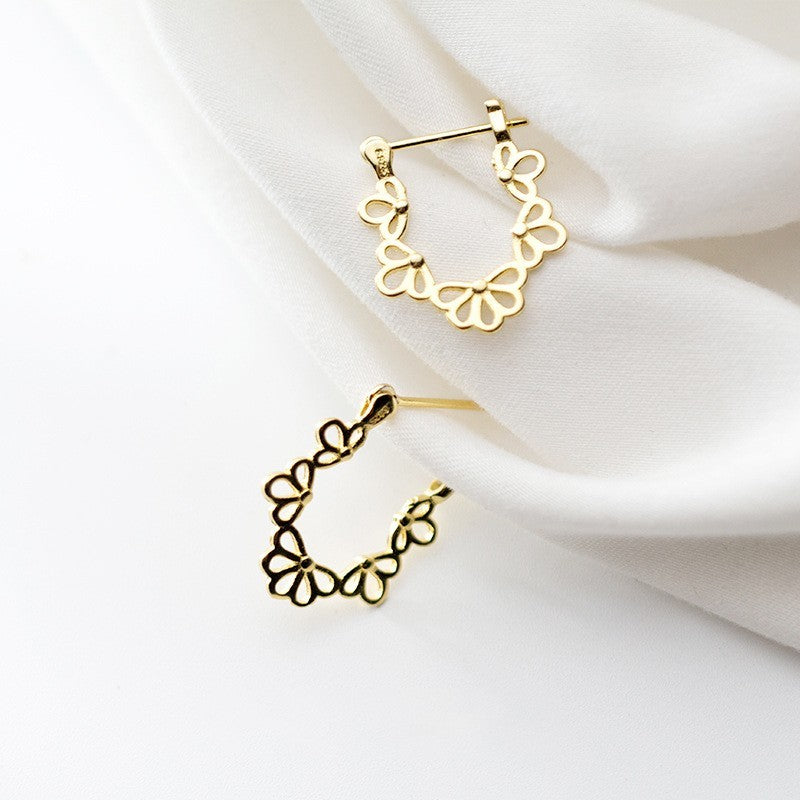 Gold hoop earrings on a white fabric background