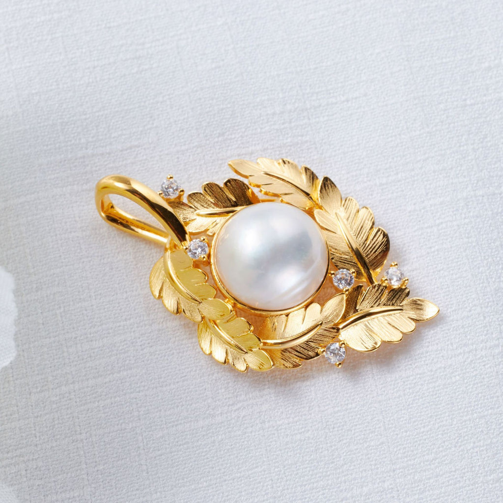 Gold pendant with a pearl and small diamonds on a light gray background