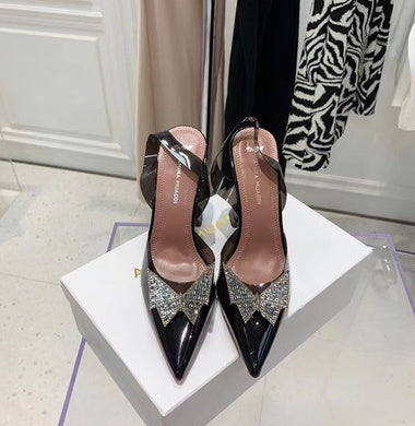 Black high-heeled shoes with decorative elements on a white box