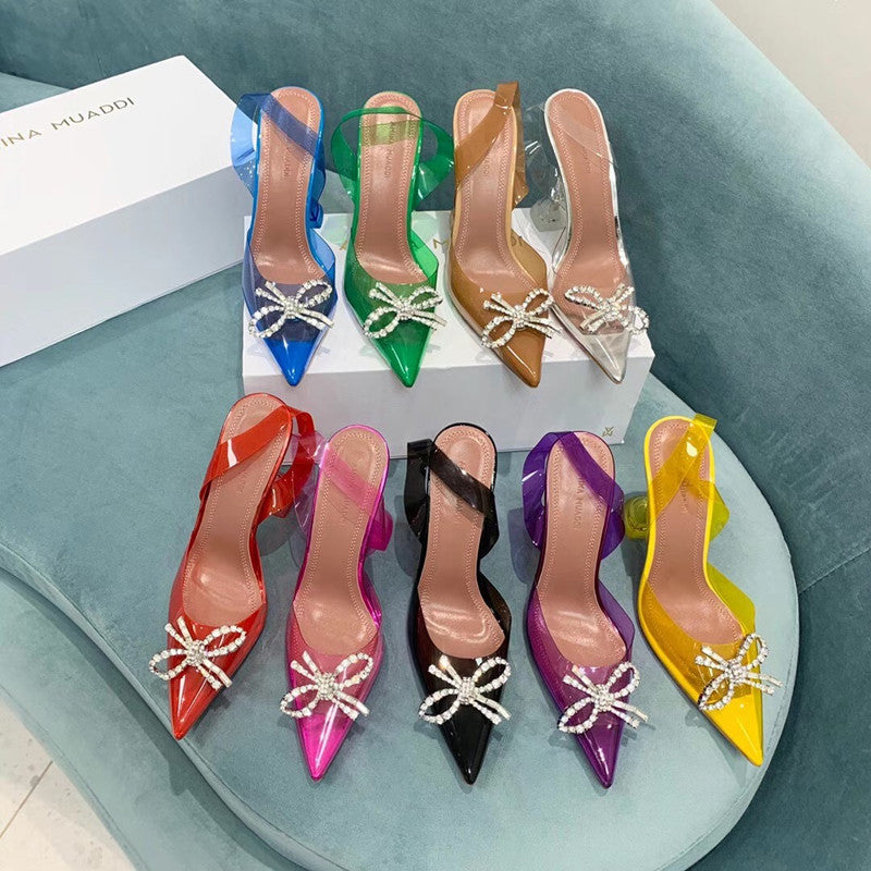 Colorful high-heeled shoes with decorative bows on a light blue surface.