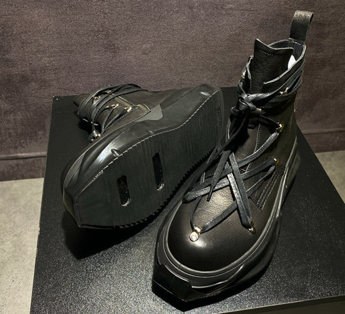 Pair of black high-top sneakers on a dark surface with a neutral background