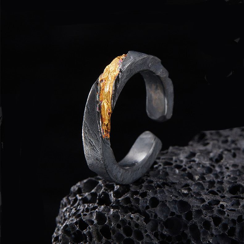 Black and gold ring on a textured black surface with a dark background