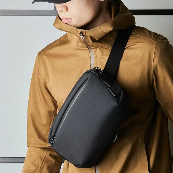 Person wearing a brown jacket with a black crossbody bag