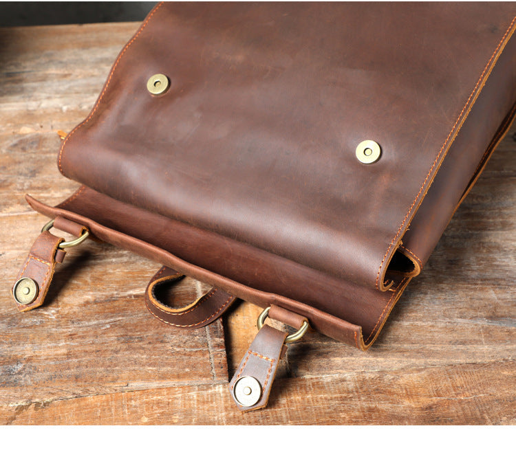 Brown leather bag with gold hardware on a wooden surface