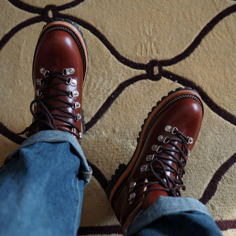 Brown leather boots with blue jeans on a patterned carpet