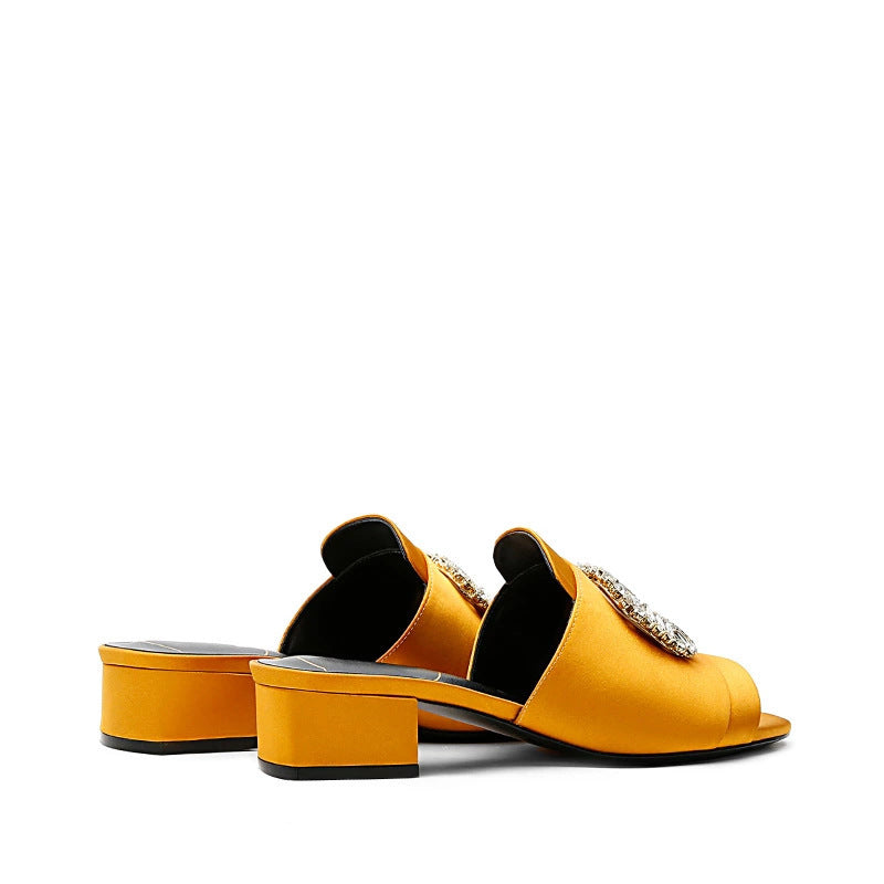 Yellow open-toe shoes with embellishments on a white background