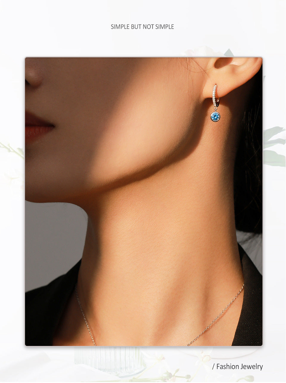 Close-up of a person wearing a blue gemstone earring with a neutral background