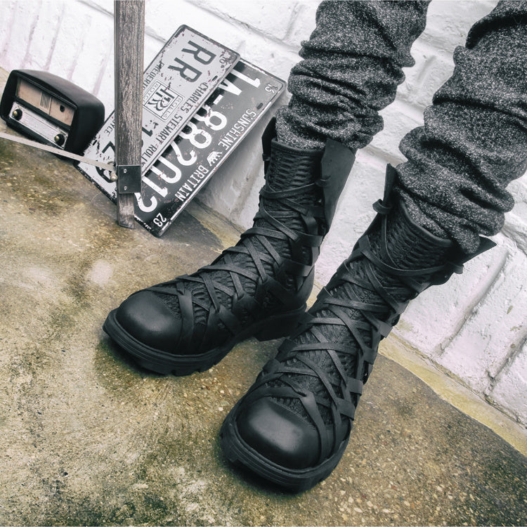 Black combat boots worn by a person sitting on a concrete surface with license plates in the background.