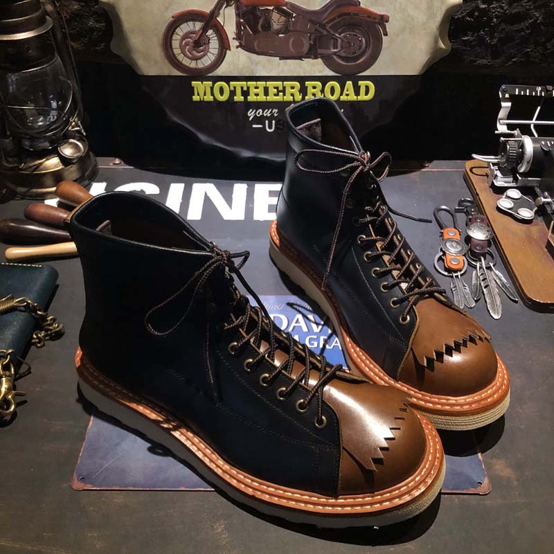 Pair of black and brown boots on a table with tools and a 'Mother Road' sign in the background.