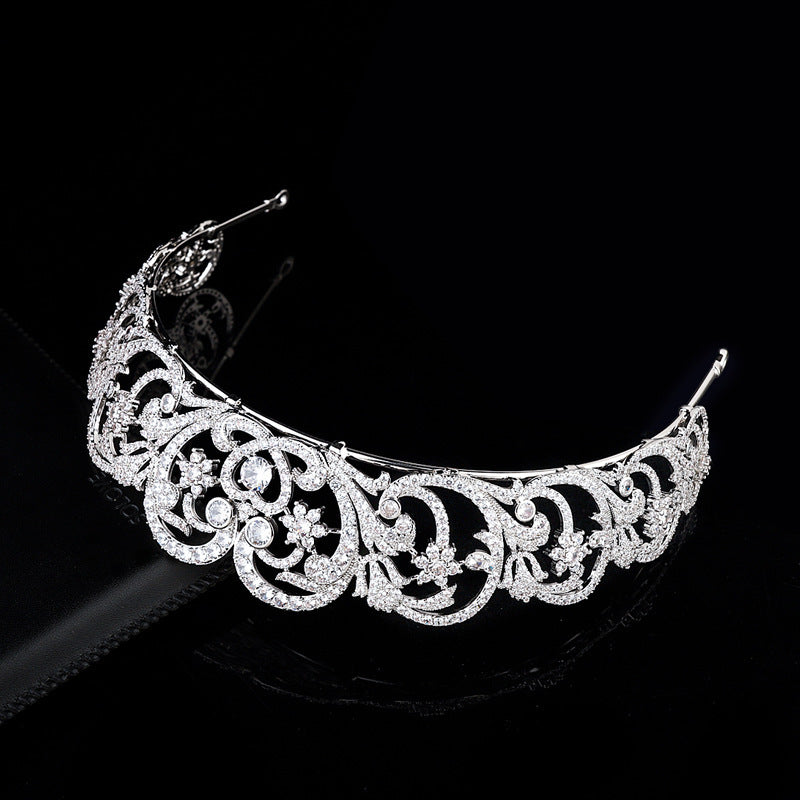 Silver tiara with intricate designs on a black background